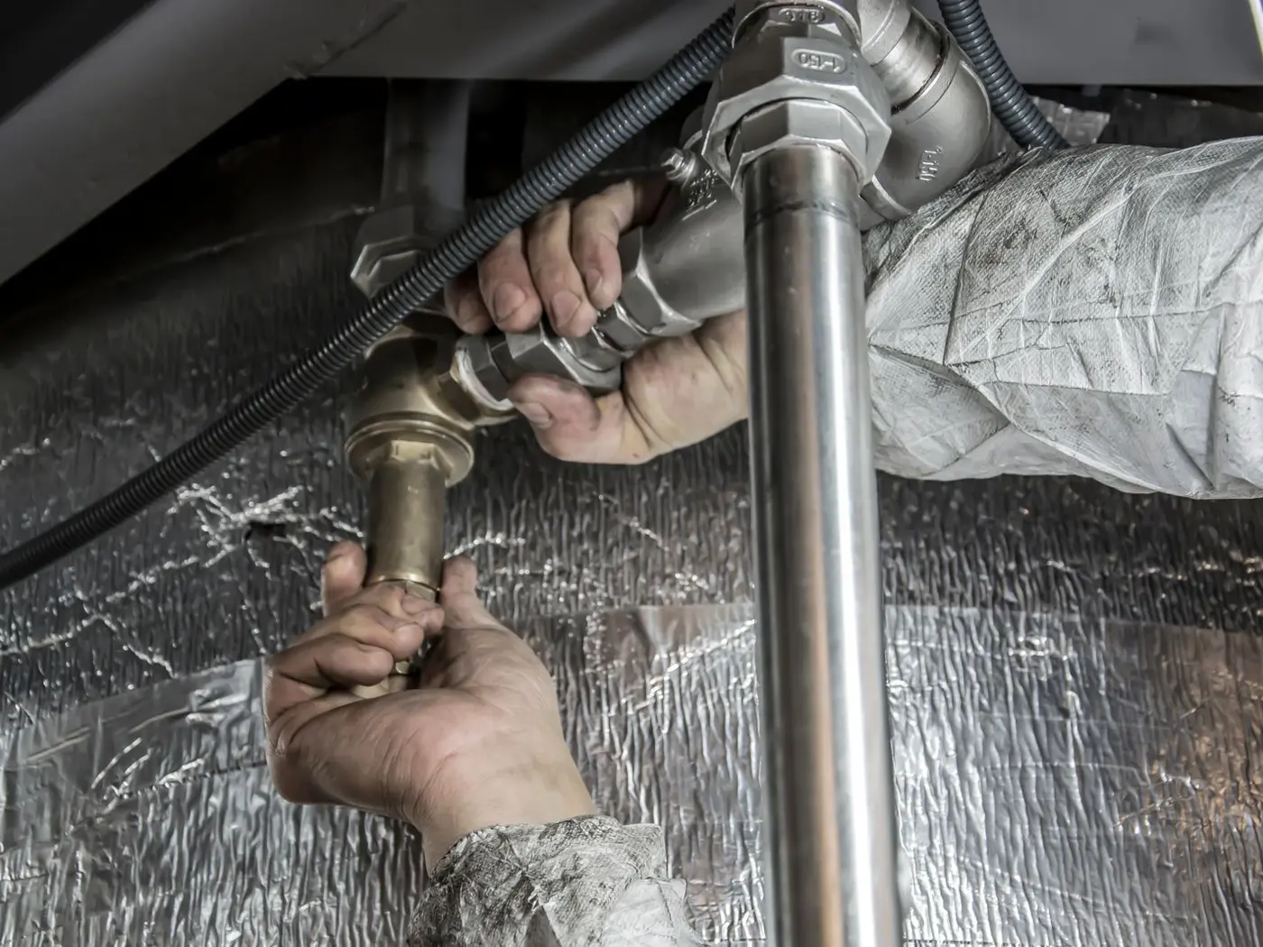Plumber tightening a brass fitting on a water supply pipe